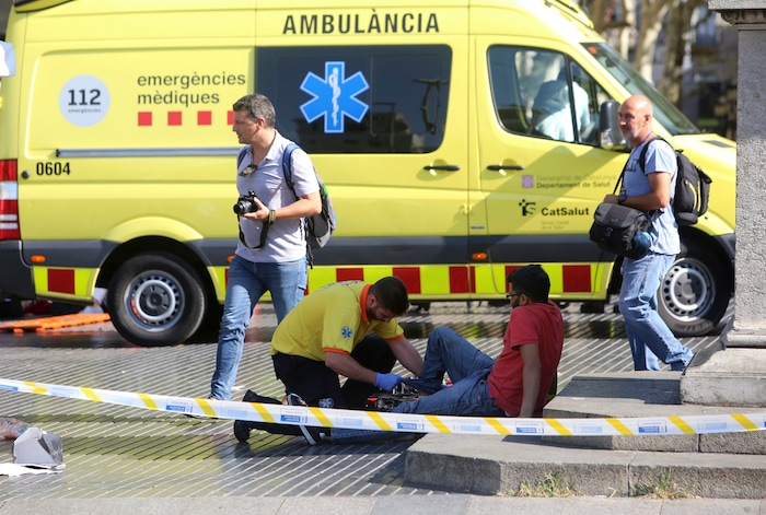 An injured person is treated in Barcelona, Spain, Thursday, Aug. 17, 2017 after a white van jumped the sidewalk in the historic Las Ramblas district, crashing into a summer crowd of residents and tourists and injuring several people, police said. (AP Photo/Oriol Duran)