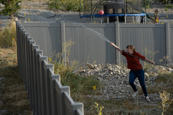 (Francisco Kjolseth  |  The Salt Lake Tribune)  Becky Hudson does her best to add some water as crews battle a grass fire behind her house in Tooele county being dubbed the Green Ravine fire as it burns on Tuesday, Sept. 3, 2019.