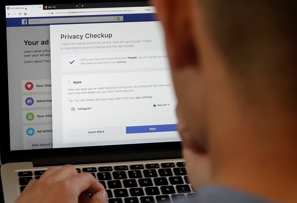 In this March 26, 2018, photo, a man poses for photos in front of a computer showing Facebook ad preferences pages in San Francisco. Facebook is giving its privacy tools a makeover as it reels from criticisms over its data practices and faces tighter European regulations in the coming months. (AP Photo/Jeff Chiu)