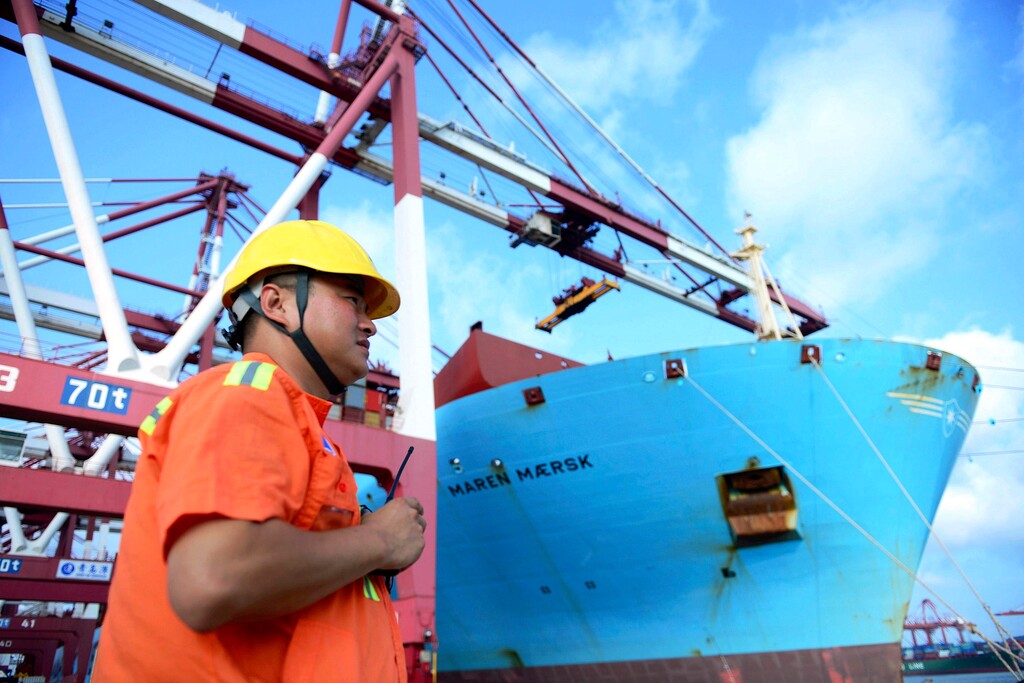 In this Aug. 8, 2018, photo, a worker stands near a container ship at a port in Qingdao in eastern China's Shandong Province. Beijing is responding to U.S. President Donald Trump’s tariff hikes by pressing companies to find more non-U.S. suppliers and customers. But there are few substitutes for the United States as a market and technology supplier. (Chinatopix via AP)