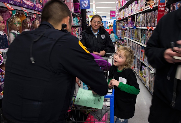 (Scott Sommerdorf   |  The Salt Lake Tribune)   
Macadia Meyer tells Officer Jose Munoz what she wanted to get for her sister while shopping in the Walmart toy aisle at the first ever Police Pay It Forward event, Saturday, December 16, 2017.