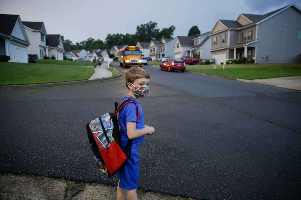 (Brynn Anderson | AP)  Paul Adamus, 7, waits at the bus stop for the first day of school on Monday, Aug. 3, 2020, in Dallas, Ga. Neighboring states arrived at differing conclusions on who’s in charge of the reopening of schools. The differences in philosophy underscore some of the difficulties facing states as they grapple with how to proceed amid growing coronavirus infections in numerous states.