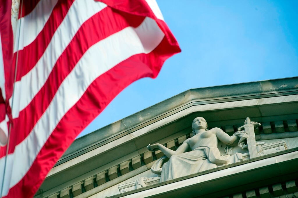 FILE - In this Nov. 2016 file photo, the American Flag flies outside the Justice Department in Washington. (AP Photo/Cliff Owen)
