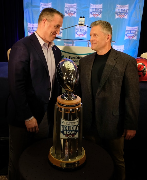 (Ken Jacques photo) Northwestern coach Pat Fitzgerald, left, and Utah's Kyle Whittingham pose with the Holiday Bowl trophy during a Dec. 10 news conference in San Diego.