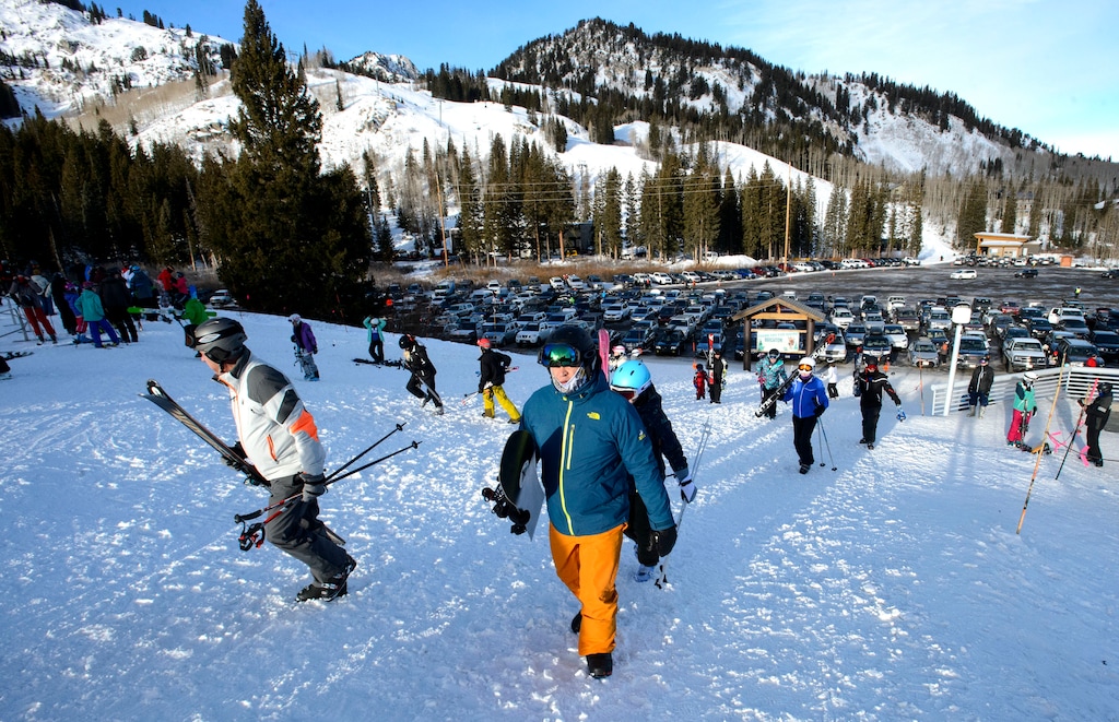 (Steve Griffin  | Salt Lake Tribune file photo) Skiers and snowboarders head up the hill to the lifts at Brighton ski area Jan. 1, 2018. Starting Wednesday, the Big Cottonwood resort will allow only skiers who carpool to park at its lot, pictured in background, on holiday, weekend and powder days. Cars with one or two occupants will have to park at the Brighton Store.