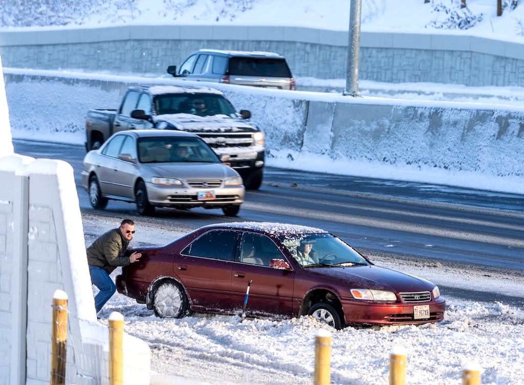 (Leah Hogsten | The Salt Lake Tribune) A man tries to help a stranded motorist on Highway 89 in Layton get her car unstuck, Dec. 2, 2022. A band of moderate to heavy snow in northern Utah in the early morning hours on Friday forced Utahns to take to their shovels and brooms to clear their walkways and vehicles and snarled traffic on roadways.