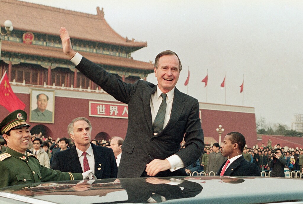FILE - In this Feb. 25, 1989, file photo, then U.S. President  George H.W. Bush stands on his car and waves to crowds in Tiananman Square in Beijing. Chinese state media are praising Bush as a "statesman of vision," recalling the late president's role in helping end the Cold War and establishing policies toward China. The China Daily newspaper said Monday, Dec. 3, 2018, that Bush in the 1980s realized China was different from the Soviet Union and recognized the potential for cooperation. (AP Photo/Doug Mills, File)