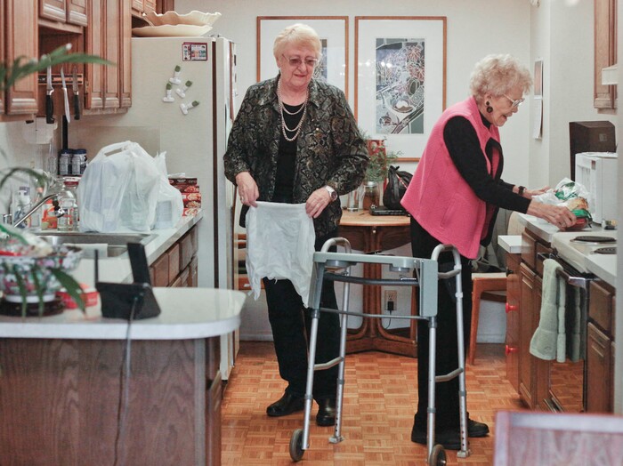 This photo taken Jan. 5, 2018, shows Marian Christensen, right, and Felicity Varkevisser, left, putting away groceries in Christensen's kitchen in Provo, Utah. The two women used to shop together during their hours together, but now Varkevisser does the shopping for Christensen. (Evan Cobb/The Daily Herald via AP)
