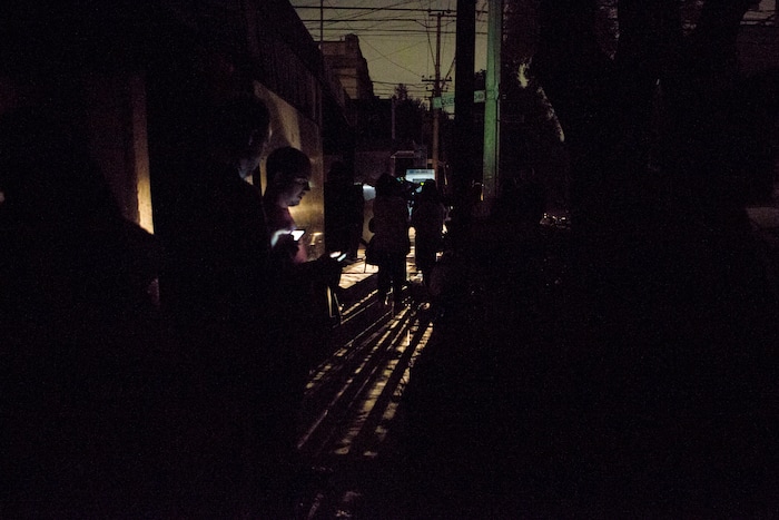 People who evacuated from bars check their phones in the street in La Roma neighborhood of Mexico City, after an earthquake shook buildings forcefully and knocked out power in the area, just before midnight on Thursday, Sept. 7, 2017. A massive earthquake hit off the coast of southern Mexico late Thursday night, causing buildings to sway violently and people to flee into o the streets in panic as far away as the capital city. (AP Photo/Rebecca Blackwell)