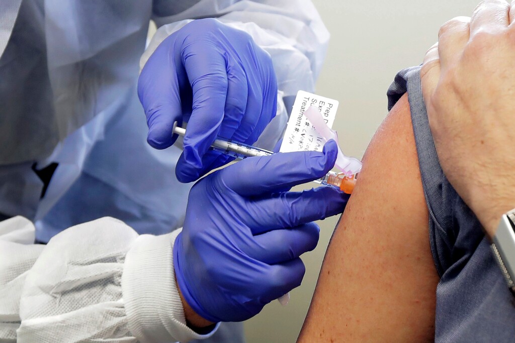 (Ted S. Warren | AP) In this March 16, 2020 file photo, a subject receives a shot in the first-stage safety study clinical trial of a potential vaccine by Moderna for COVID-19, the disease caused by the new coronavirus, at the Kaiser Permanente Washington Health Research Institute in Seattle. Britain, the United States and Canada accused Russia on Thursday July 16, 2020, of trying to steal information from researchers seeking a COVID-19 vaccine.