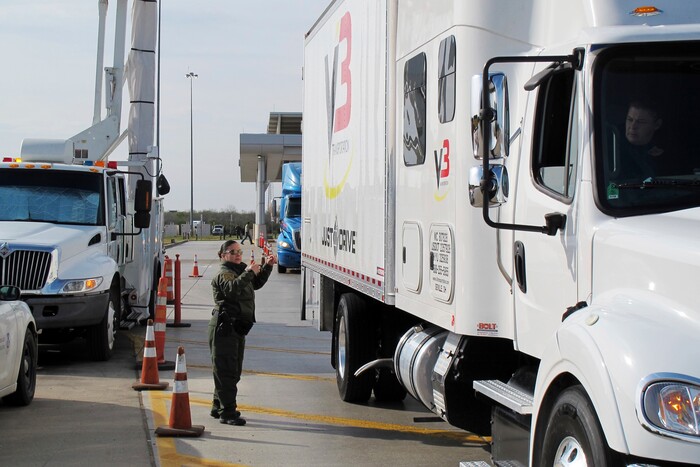 Border Patrol agent Gracie Briones waves through a tractor-trailer after it passed through an X-ray machine at the Laredo North checkpoint in Laredo, Texas, on Friday, February 2, 2018. Only a fraction of tractor-trailers undergo a scan in by the machine, which allows agents to check for any signs of humans or drugs hidden inside. (AP Photo/Nomaan Merchant)