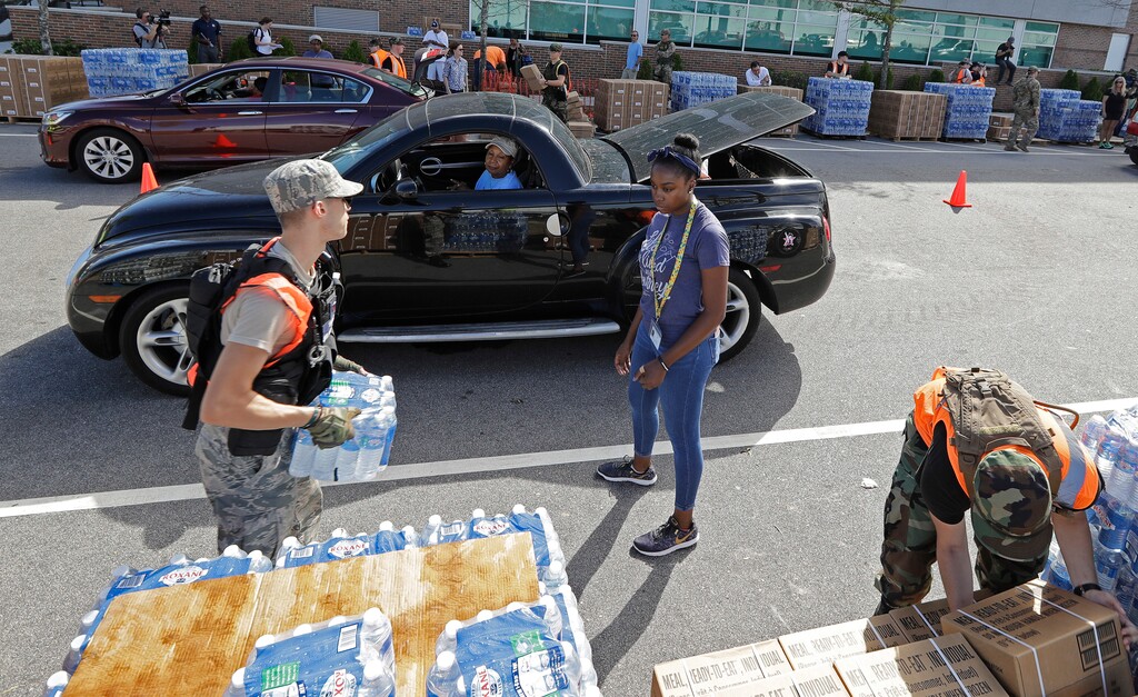 Members of the Civil Air Patrol load cars with MREs, (Meals Ready To Eat) water and tarps at distribution area in Wilmington, N.C. Tuesday, Sept. 18, 2018. (AP Photo/Chuck Burton)