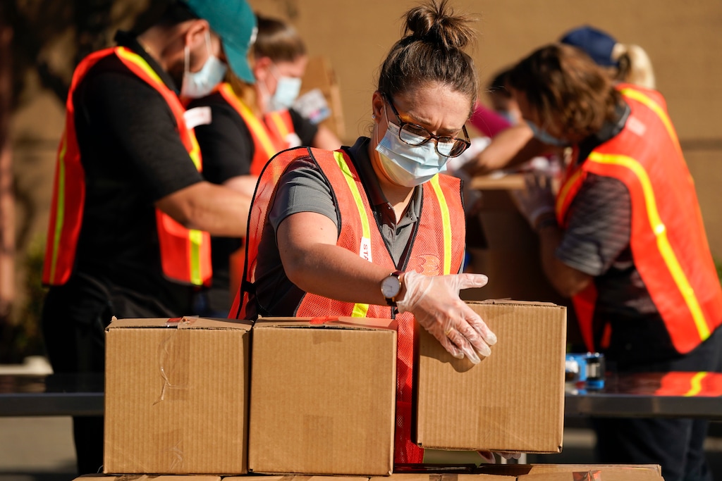 (Ashley Landis | AP) Kristen McKenna and other volunteers pack boxes of food outside Second Harvest Food Bank on Thursday, Nov. 19, 2020, in Irvine, Calif.