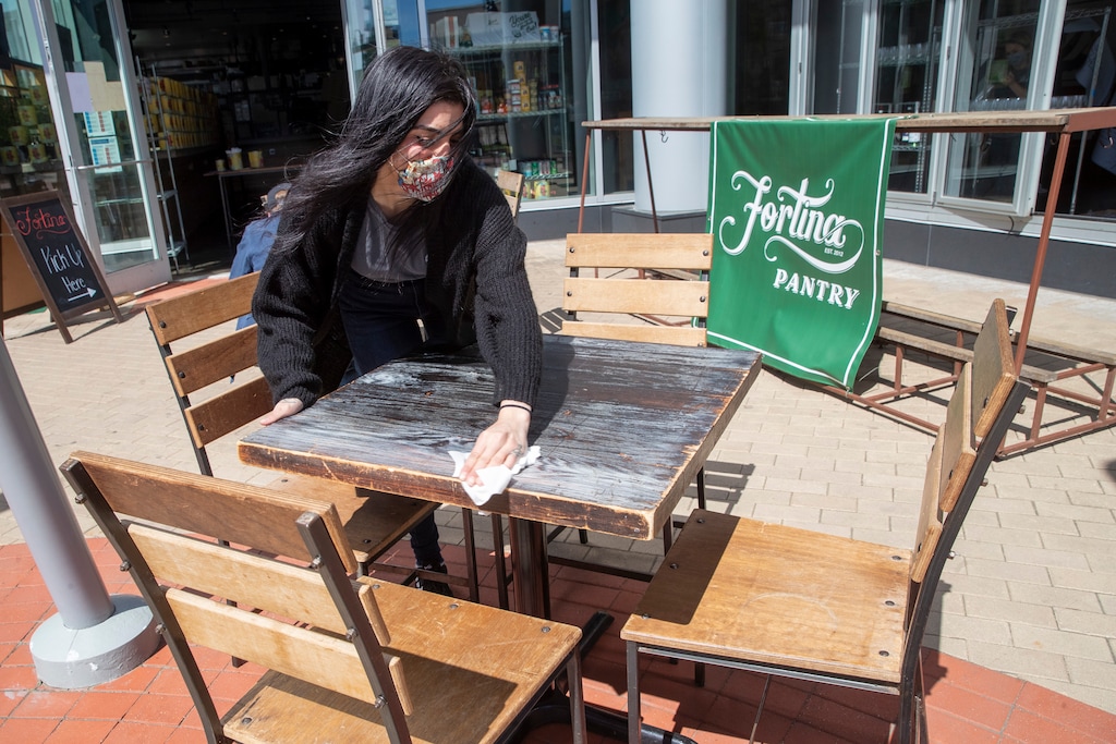 An employee at Fortina restaurant disinfects an outdoor table in preparation for the opening of outdoor dining, Wednesday, May 20, 2020, in Stamford, Conn. Restaurants can begin offering service in outdoor dining areas Wednesday as part of the first phase of Connecticut's statewide reopening, including in hard-hit Fairfield County on the New York state line. (AP Photo/Mary Altaffer)