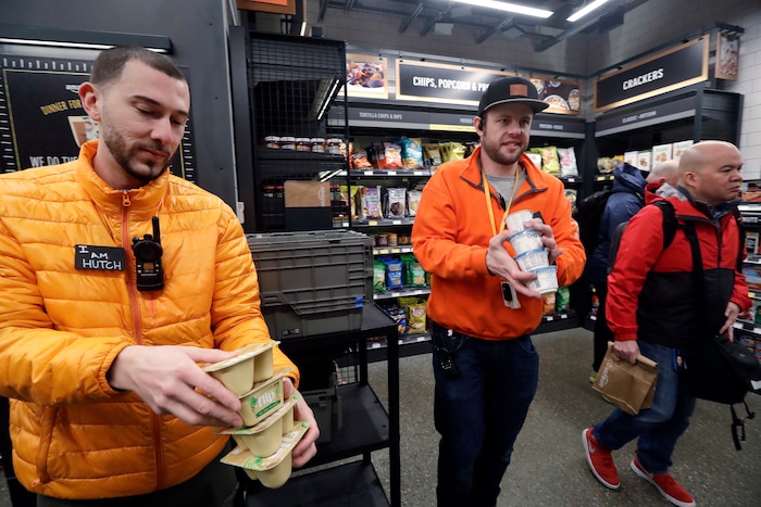 Store employees Tyler "Hutch" Hutchinson, left, and Eric Halgren stock shelves at an Amazon Go store, Monday, Jan. 22, 2018, in Seattle. The artificial intelligence-powered store, which opened to the public on Monday, allows shoppers to scan their smartphone with the Amazon Go app at a turnstile, pick out the items they want and leave. The online retail giant can tell what people have purchased and automatically charges their Amazon account. (AP Photo/Elaine Thompson)
