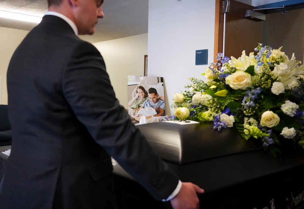 (Bethany Baker | The Salt Lake Tribune) A photograph of Tanner Martin holding his daughter Amy Lou Martin as he sits beside his wife Shay Wright is seen behind MartinÕs casket as it is wheeled out to the hearse following the funeral services for Martin, the man who chronicled his cancer battle alongside his wife's pregnancy, in American Fork on Saturday, July 5, 2025.