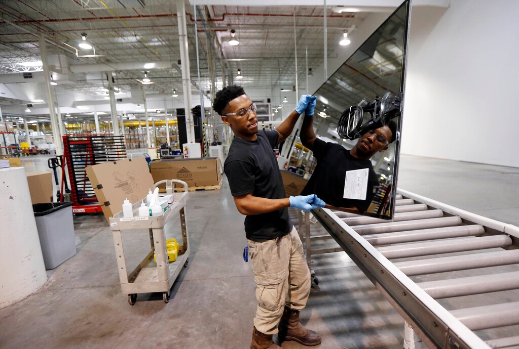 FILE- In this June 15, 2016, photo, Ricky Foster gingerly carries a completed solar panel to a shipping case after inspecting and cleaning its surface at Stion, a solar panel maker in Hattiesburg, Miss. On Thursday, Feb. 15, 2018, the Federal Reserve reports on U.S. industrial production for January. (AP Photo/Rogelio V. Solis, File)