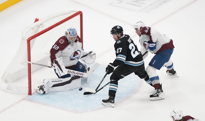 (Bethany Baker | The Salt Lake Tribune) Colorado Avalanche goaltender Justus Annunen (60) blocks a shot as Utah Hockey Club center Barrett Hayton (27) tries to score while Colorado Avalanche defenseman Josh Manson (42) defends during the game between the Utah Hockey Club and the Colorado Avalanche at the Delta Center in Salt Lake City on Thursday, Oct. 24, 2024.