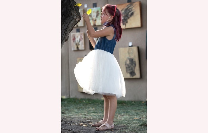 (Rick Egan | The Salt Lake Tribune) Alice Silvester 8, plays with leaves in a tree at the Salt Lake Arts Festival, on Saturday, Aug. 28, 2021.