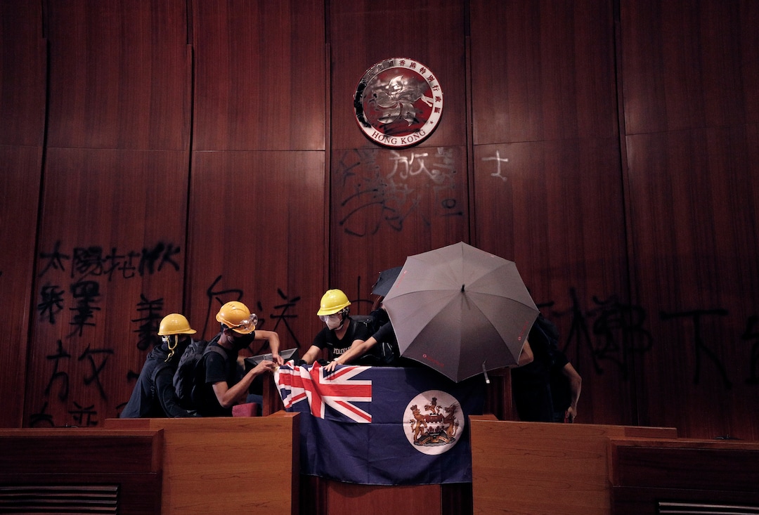 (Vincent Yu | AP Photo) Protesters put a Hong Kong colonial flag and deface the Hong Kong logo at the Legislative Chamber after they broke into the Legislative Council building in Hong Kong, Monday, July 1, 2019. Hundreds of protesters in Hong Kong swarmed into the legislature's main building Monday night, tearing down portraits of legislative leaders and spray-painting pro-democracy slogans on the walls of the main chamber as frustration over a lack of response from the administration to opposition demands boiled over.