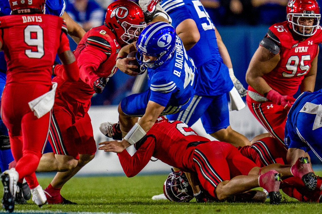 (Trent Nelson  |  The Salt Lake Tribune) BYU Cougars quarterback Bear Bachmeier (47) leaps over a Utah defender as BYU hosts Utah, NCAA football at LaVell Edwards Stadium in Provo on Saturday, Oct. 18, 2025.