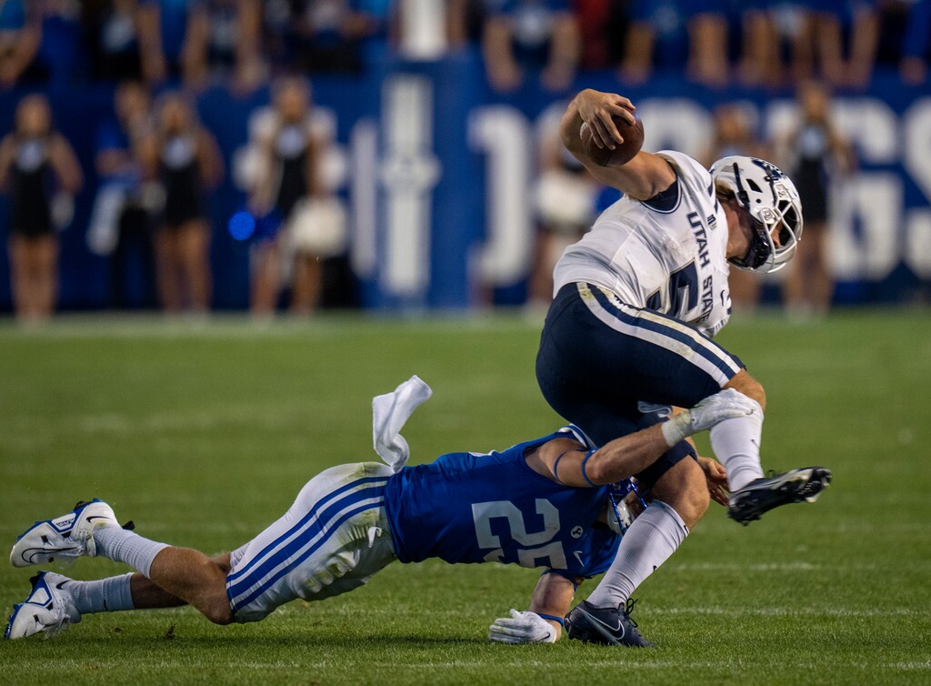 (Rick Egan | The Salt Lake Tribune) Brigham Young Cougars defensive back Talan Alfrey (25) brings down Utah State Aggies quarterback Cooper Legas (5), in Football action between the Brigham Young Cougars and the Utah State Aggies, at LaVell Edwards Stadium in Provo, on Thursday, Sept. 29, 2022.