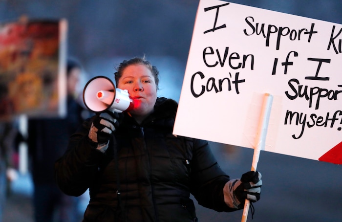 Rebecca Basal uses a bullhorn to lead fellow striking teachers in a chant as they walk a picket line outside the school early Monday, Feb. 11, 2019, in Denver. The strike on Monday is the first for teachers in Colorado in 25 years after failed negotiations with the school district over base pay. (AP Photo/David Zalubowski)