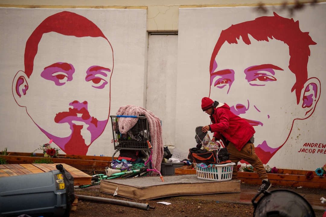 (Trent Nelson  |  The Salt Lake Tribune) A person sorts through their belongings as Salt Lake County conducts a camp cleanup at the Fleet Block Murals in Salt Lake City on Wednesday, April 14, 2021.