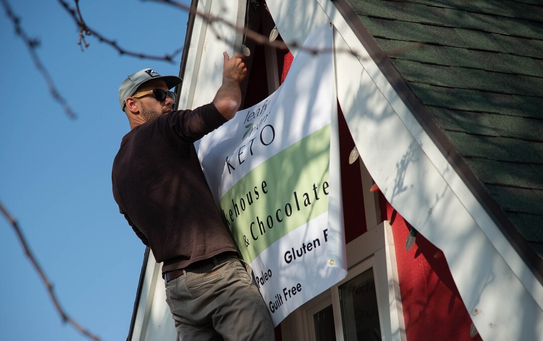 (Francisco Kjolseth  |  The Salt Lake Tribune) Cameron Edwards helps set up signage on the iconic Sugarhouse ‘Santa Shack,” being transformed into a new gluten-free bakery called The Keto Bakehouse. Cameron’s mother Melanie Edwards plans to open on Thursday, Oct. 8, selling gluten-free, low carb, no-sugar cookies, cakes, brownies, cupcakes, chocolates, trail mixes, and energy bars.