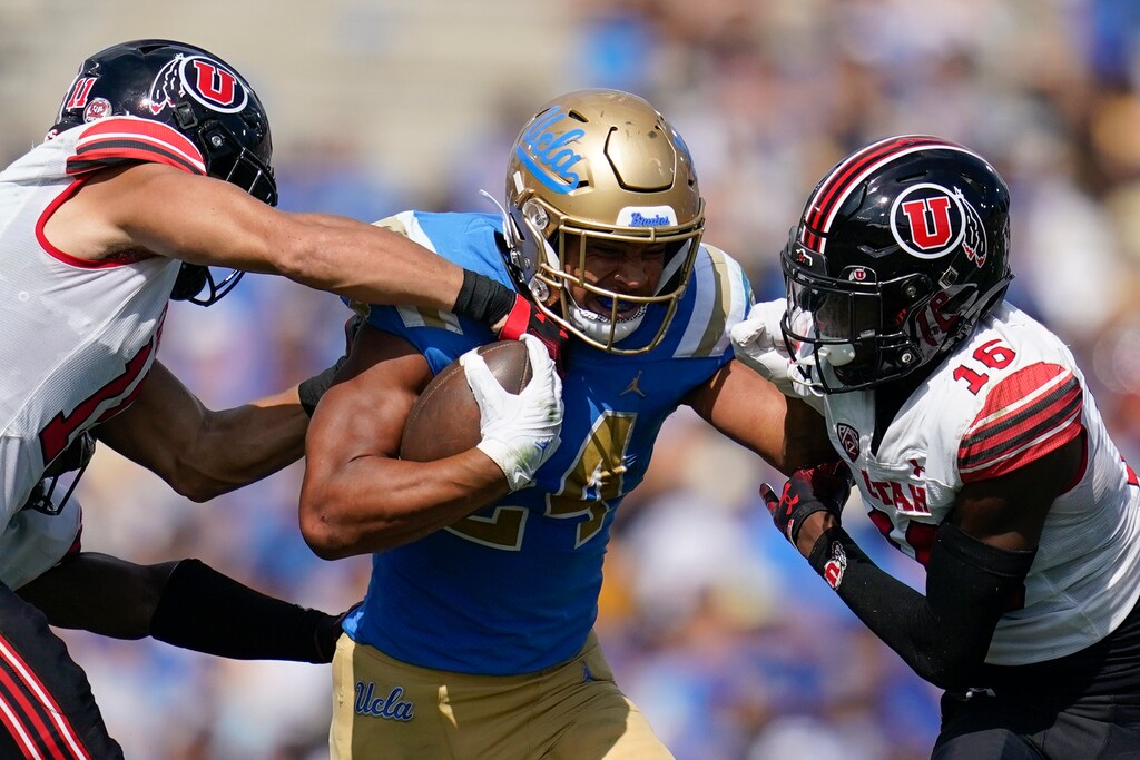 (Ashley Landis | AP) UCLA running back Zach Charbonnet (24) is tackled by Utah safety R.J. Hubert (11) and cornerback Zemaiah Vaughn (16) during the first half of an NCAA college football game in Pasadena, Calif., Saturday, Oct. 8, 2022.