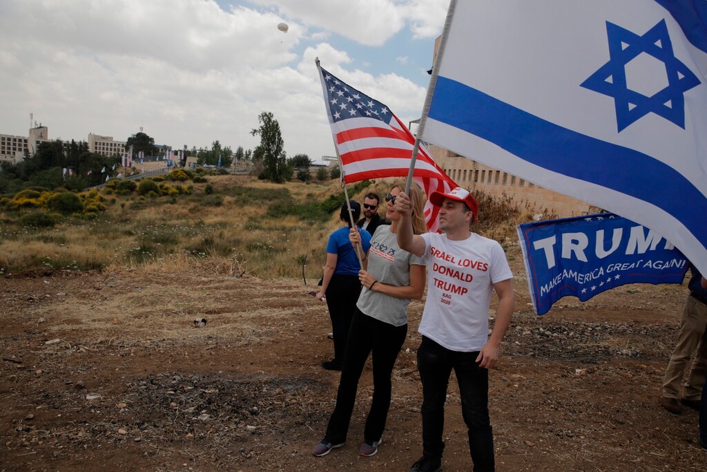 Israelis hold American and Israeli flags with the new U.S. embassy in the background in Jerusalem, Monday, May 14, 2018. (AP Photo/Sebastian Scheiner)