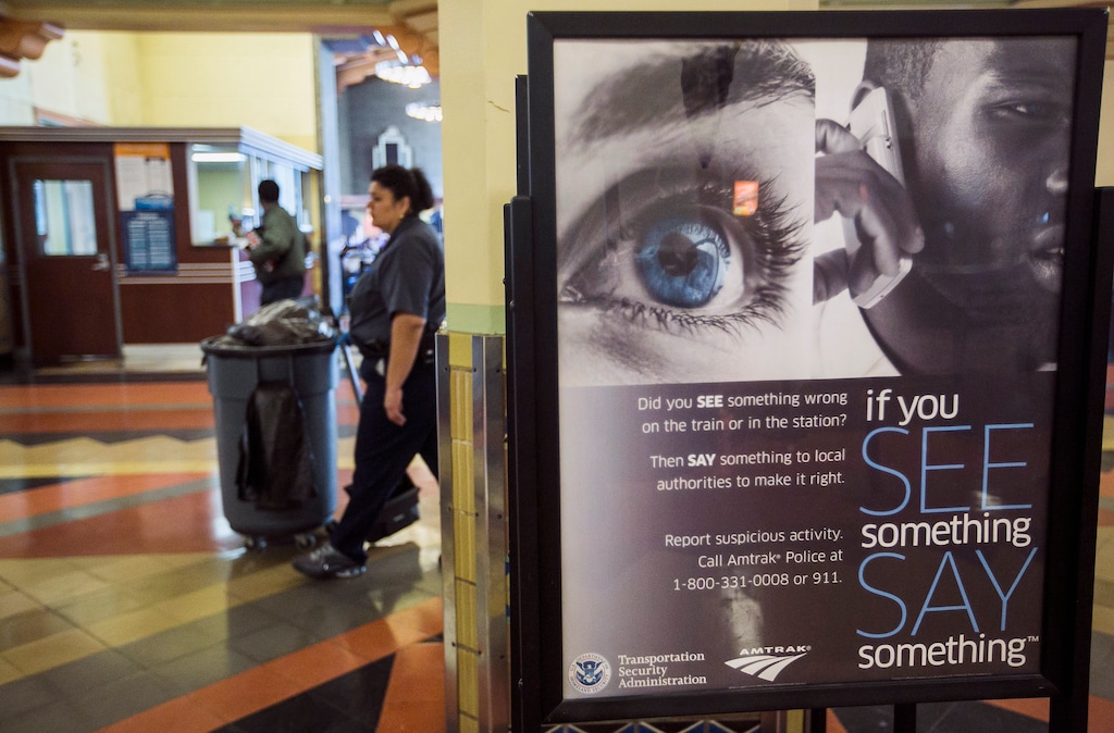 (AP Photo/Damian Dovarganes) A janitor walks past Transportation Security Administration sign reading: "If you See Something, Say Something," to encourage citizens to report suspicious activities at Union Station on Tuesday, April 16, 2013.