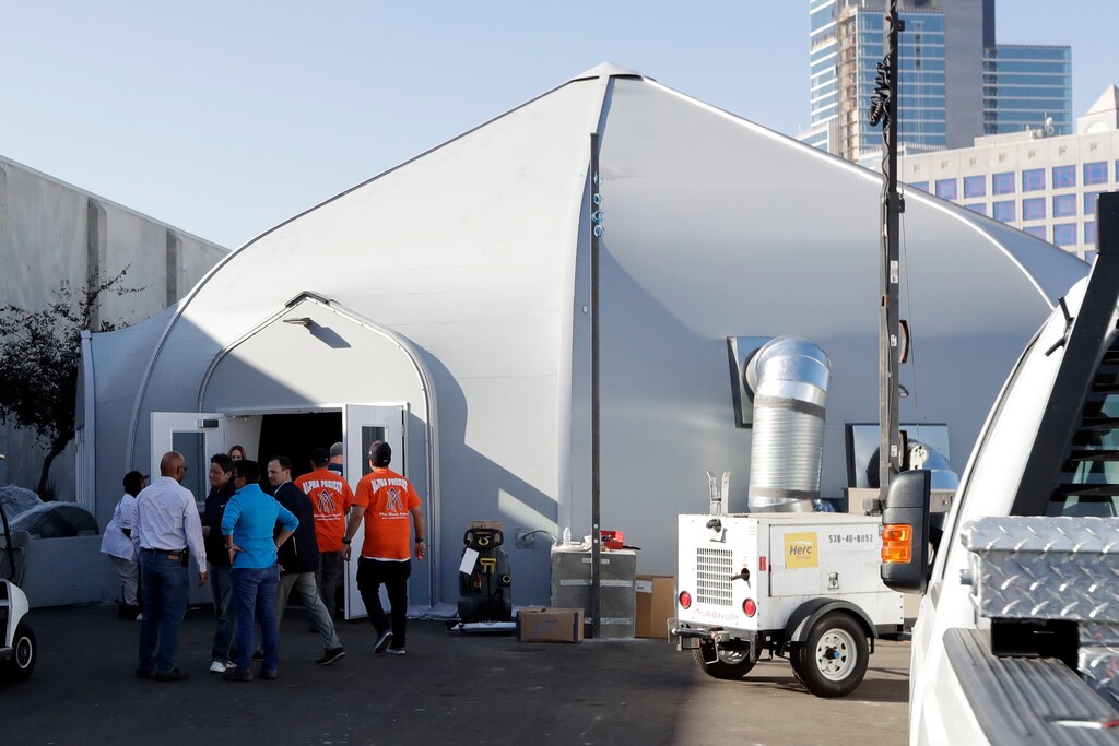 Crews work in front of the the city's new Temporary Bridge Shelter for the homeless Friday, Dec. 1, 2017, in San Diego. The first of three shelters opened Friday, which will eventually provide beds for up to 700 people, as the city struggles to control a homeless crisis gripping the region. (AP Photo/Gregory Bull)