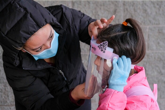 (Leah Hogsten | The Salt Lake Tribune) Escalante Elementary first grader Sophia gets her face shield adjusted by her mother Theresa before she heads back into the classroom in Salt Lake City, January, 25, 2021. Salt Lake City School District reopened all of the district's elementary schools to in-person learning on Monday. It is the first time students in kindergarten through sixth grade are back in the classroom for a full day of school since they first closed for the pandemic in March 2020.