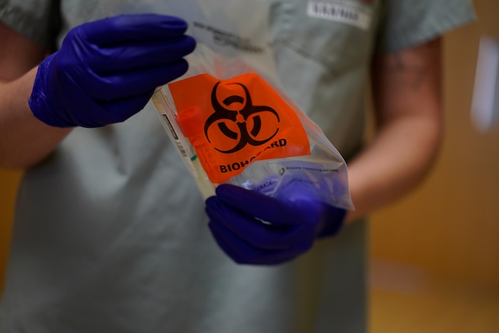 Team Rubicon volunteer, EMT Hannah Tellier, from Boston, holds a COVID-19 test in the emergency room of the Kayenta Health Center on the Navajo reservation in Kayenta, Ariz., on April 23, 2020. The Navajo reservation has some of the highest rates of coronavirus in the country. Team Rubicon is helping with medical operations as cases of COVID-19 surge. (AP Photo/Carolyn Kaster)