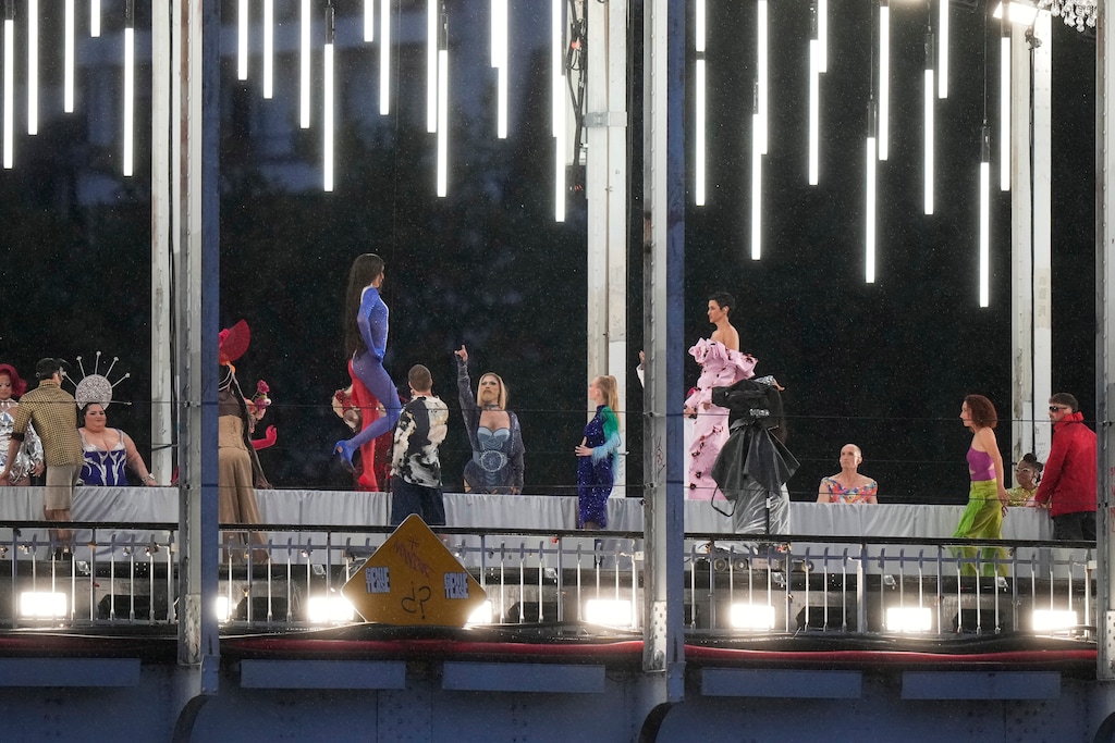 (Andrew Medichini | AP) Models walk during a fashion show over the Seine River bridge in Paris at the Opening Ceremony of the 2024 Summer Olympics on Friday, July 26, 2024.