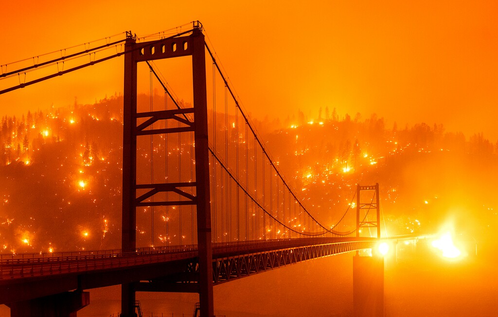 (Noah Berger | AP) In this image taken with a slow shutter speed, embers light up a hillside behind the Bidwell Bar Bridge as the Bear Fire burns in Oroville, Calif., on Wednesday, Sept. 9, 2020. The blaze, part of the lightning-sparked North Complex, expanded at a critical rate of spread as winds buffeted the region.