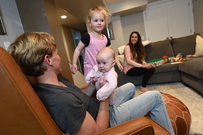 (Francisco Kjolseth | The Salt Lake Tribune) Scott Allen juggles his daughters Cora, 11-weeks, and Audrey, 3, at their home in Salt Lake on Thursday, May 3, 20018. Scott and his wife Rachel, in background, both anesthesiologists in a burn unit are trying to balance a free range childhood with safety practices to prevent their kids experiencing the injuries they witness at work every day. Utah is believed to be the first state to pass a law that prevents parents from being prosecuted for allowing mature kids with good judgement to do things alone, provided they are otherwise cared for.