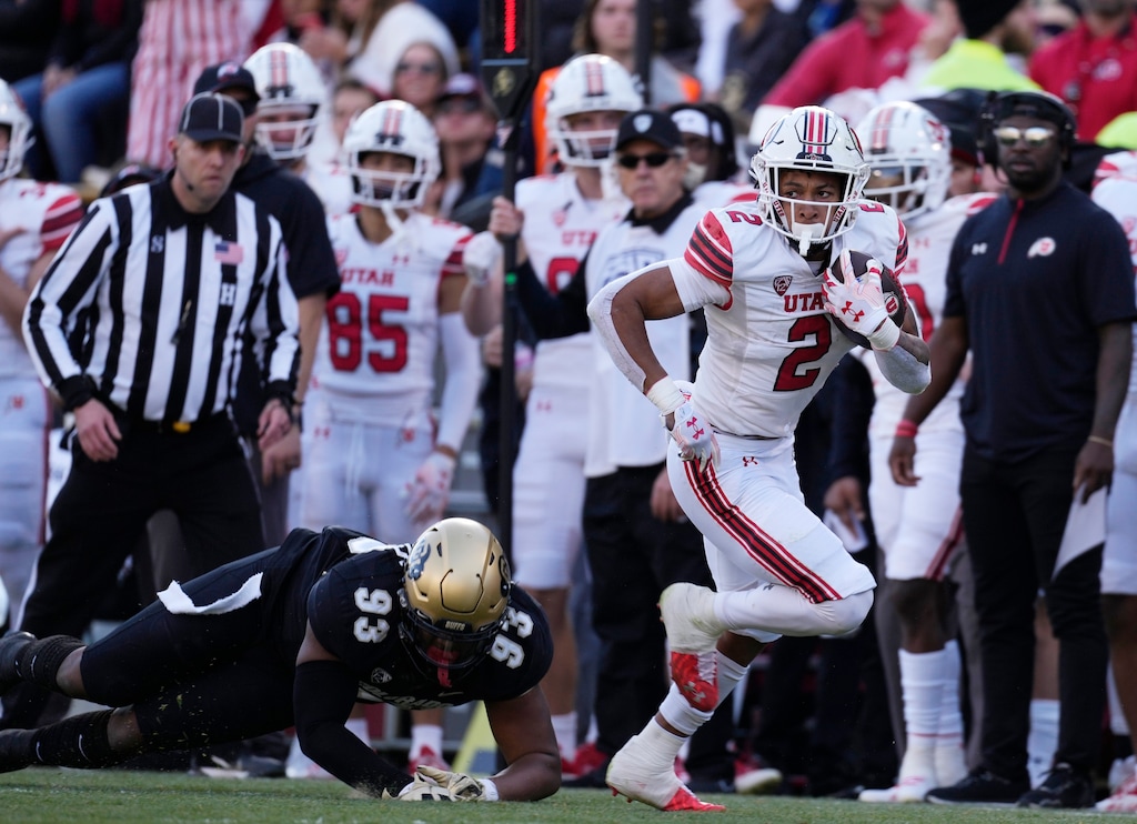 Utah running back Micah Bernard, right, heads up the sideline after pulling in a pass in front of Colorado defensive lineman Ryan Williams in the first half of an NCAA college football game Saturday, Nov. 26, 2022, in Boulder, Colo. (AP Photo/David Zalubowski)