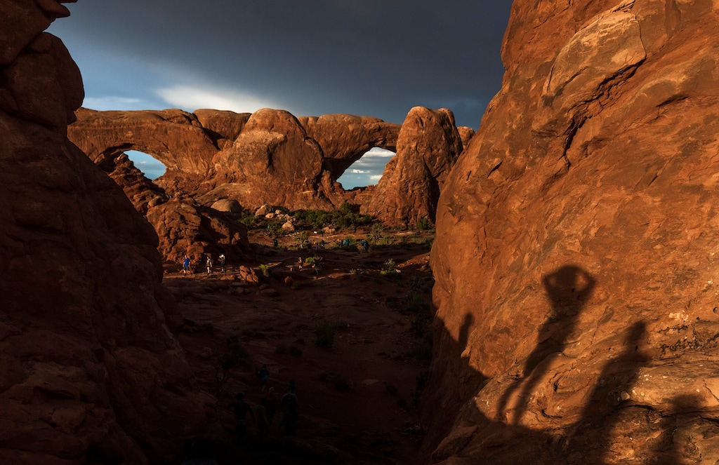 (Leah Hogsten | The Salt Lake Tribune) Visitors climb the sandstone at Turret Arch, left and The Windows, right, in Arches National Park, Monday, May 15, 2023. In April 2023, Arches National Park implemented a timed entry system to pace visitors' arrival times to alleviate overcrowding and congestion among some 1.8 million visitors a year.