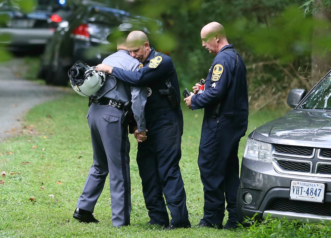 Authorities embrace while working near the scene of a deadly helicopter crash near Charlottesville, Va., on Saturday Aug. 12, 2017. (Shelby Lum/Richmond Times-Dispatch via AP)
