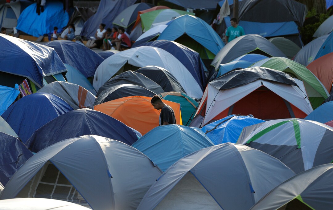In this Tuesday, Nov. 5, 2019, photo, a migrant walks through a refugee camp in Matamoros, Mexico. The camp is an outgrowth of the Trump administration’s “Remain in Mexico” program, in which more than 55,000 migrants seeking entry into the U.S. have been ordered to pursue their cases outside its borders. (AP Photo/Eric Gay)