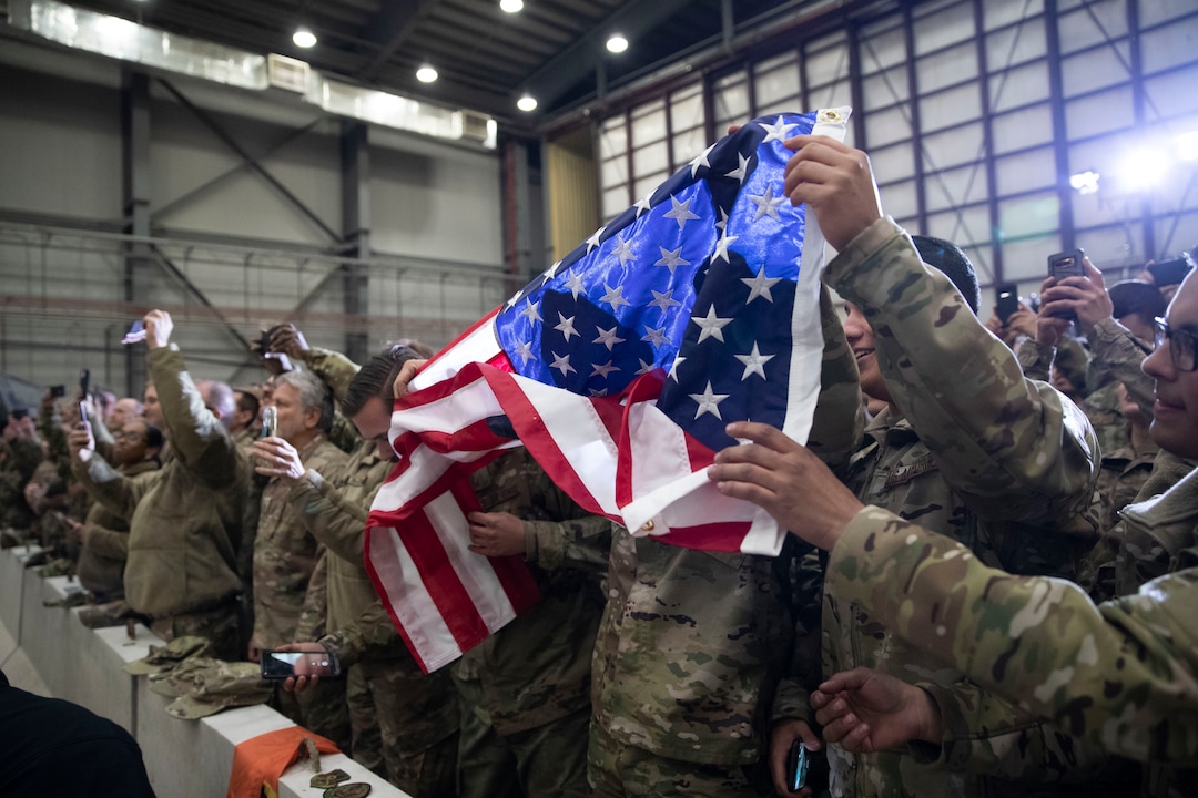 (Alex Brandon | AP) Members of the military unfurl an American flag as President Donald Trump speaks during a surprise Thanksgiving Day visit to the troops, Thursday, Nov. 28, 2019, at Bagram Air Field, Afghanistan.