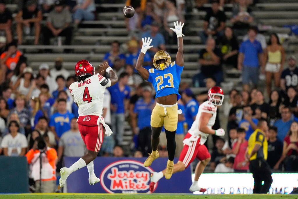 Utah quarterback Devon Dampier, left, throws a touchdown pass as UCLA defensive back Bryon Threats tries to defend during the first half of an NCAA college football game, Saturday, Aug. 30, 2025, in Pasadena, Calif. (AP Photo/Mark J. Terrill)