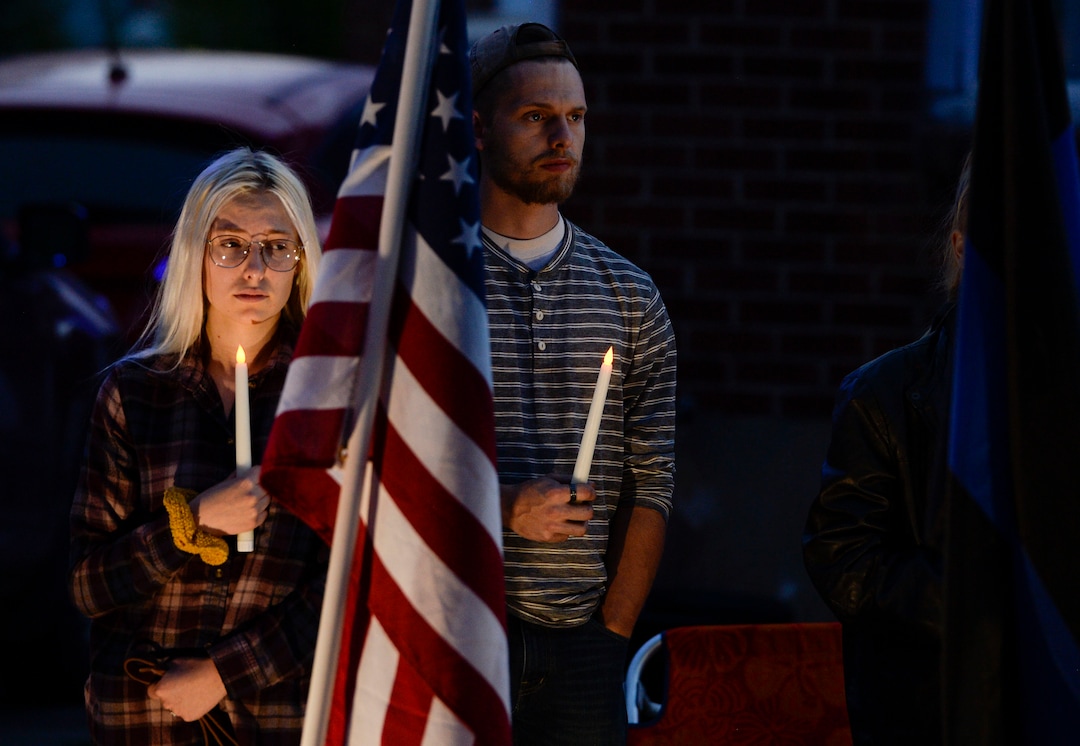 (Leah Hogsten  |  The Salt Lake Tribune) Officer Nate Lyday's cousins Jacquelyn Mesmer and brother Bronson Mesmer stood in the yard of Lyday's mother's home as the procession passed. Ogden Police Department vehicles drive past Officer Nate LydayÕs childhood home on Custer Avenue in Ogden in a Memorial Procession and Community Vigil in honor of Lyday's life. The procession made its way through five other Ogden landmarks before ending at Lindquist Field.