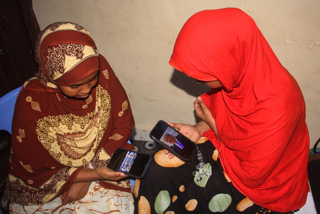 (Farah Abdi Warsameh | AP) Somali women watch a speech by U.S. president Donald Trump on their phones in Mogadishu, Somalia, Wednesday, Dec. 3, 2025.