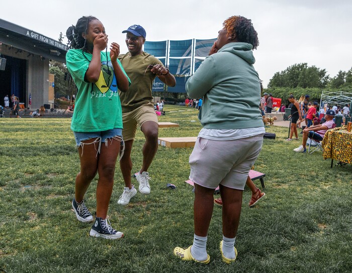 (Leah Hogsten | The Salt Lake Tribune) Iyannah Sawyer, left, and her friend Malachi Marsalis, right, laugh at the antics and dancing of Sawyer's uncle Omar Sawyer at the Utah Juneteenth Celebration at the Ogden City Amphitheater, Saturday, June 18, 2022. 