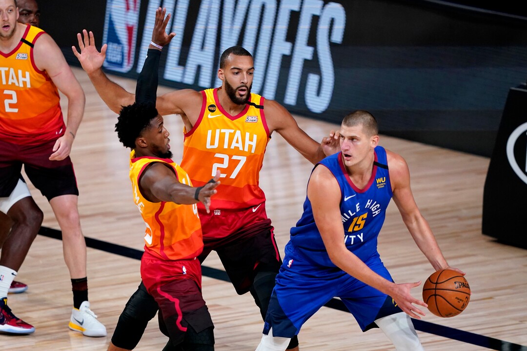 Denver Nuggets' Nikola Jokic (15) looks to pass under pressure from Utah Jazz's Rudy Gobert (27) and Donovan Mitchell during the first half of an NBA basketball first round playoff game Friday, Aug. 21, 2020, in Lake Buena Vista, Fla. (AP Photo/Ashley Landis, Pool)