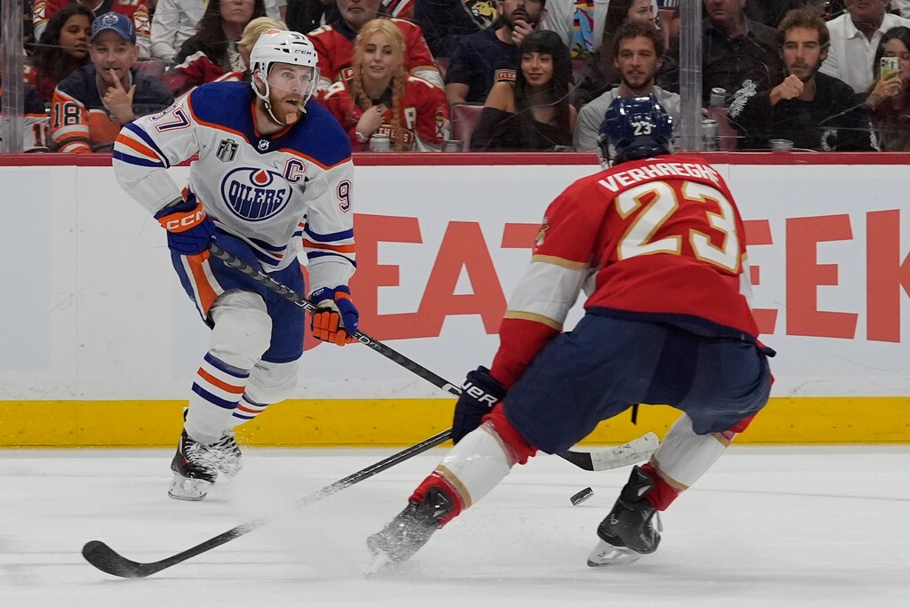 Edmonton Oilers center Connor McDavid (97) passes past Florida Panthers center Carter Verhaeghe (23) during the third period of Game 1 of the NHL hockey Stanley Cup Finals, Saturday, June 8, 2024, in Sunrise, Fla. (AP Photo/Wilfredo Lee)