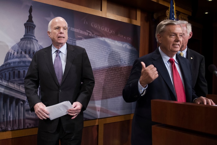FILE - In this July 27, 2017, file photo, Sen. John McCain, R-Ariz., left, walks onstage as Lindsey Graham, R-S.C., center, points to him while Sen. Ron Johnson, R-Wis., watches as they speak to reporters at the Capitol as the Republican-controlled Senate were unable to fulfill their political promise to repeal and replace "Obamacare" because of opposition and wavering within the GOP ranks, on Capitol Hill in Washington. Sen. McCain says on Friday, Sept. 22, 2017, he won't vote for the Republican bill repealing the Obama health care law. His statement likely deals a fatal blow to the last-gasp GOP measure in a Senate showdown expected next week. The Arizona Republican says he can't back the partisan GOP measure because "we could do better working together, Republicans and Democrats."  (AP Photo/Cliff Owen, File)